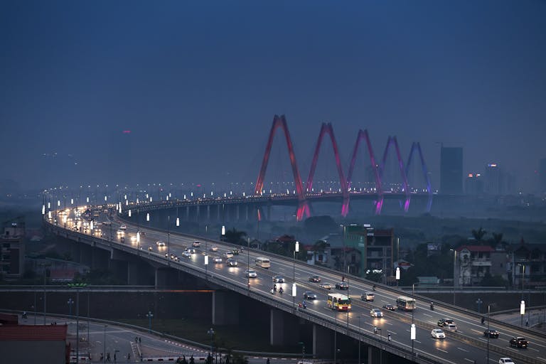 Scenic twilight view of an illuminated city bridge and road, capturing vibrant evening traffic.