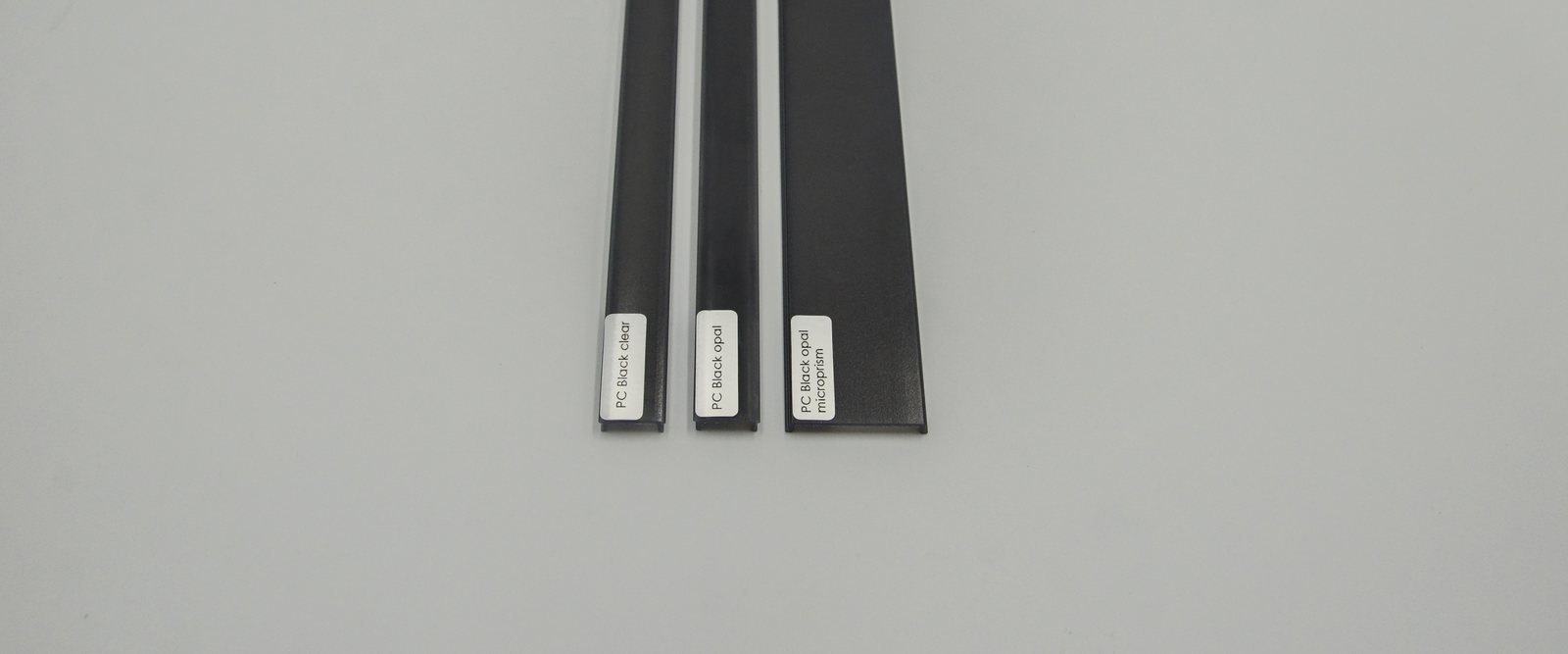 Three black anodized LED aluminum profiles with black PC diffuser covers in clear, opal and microprism finishes