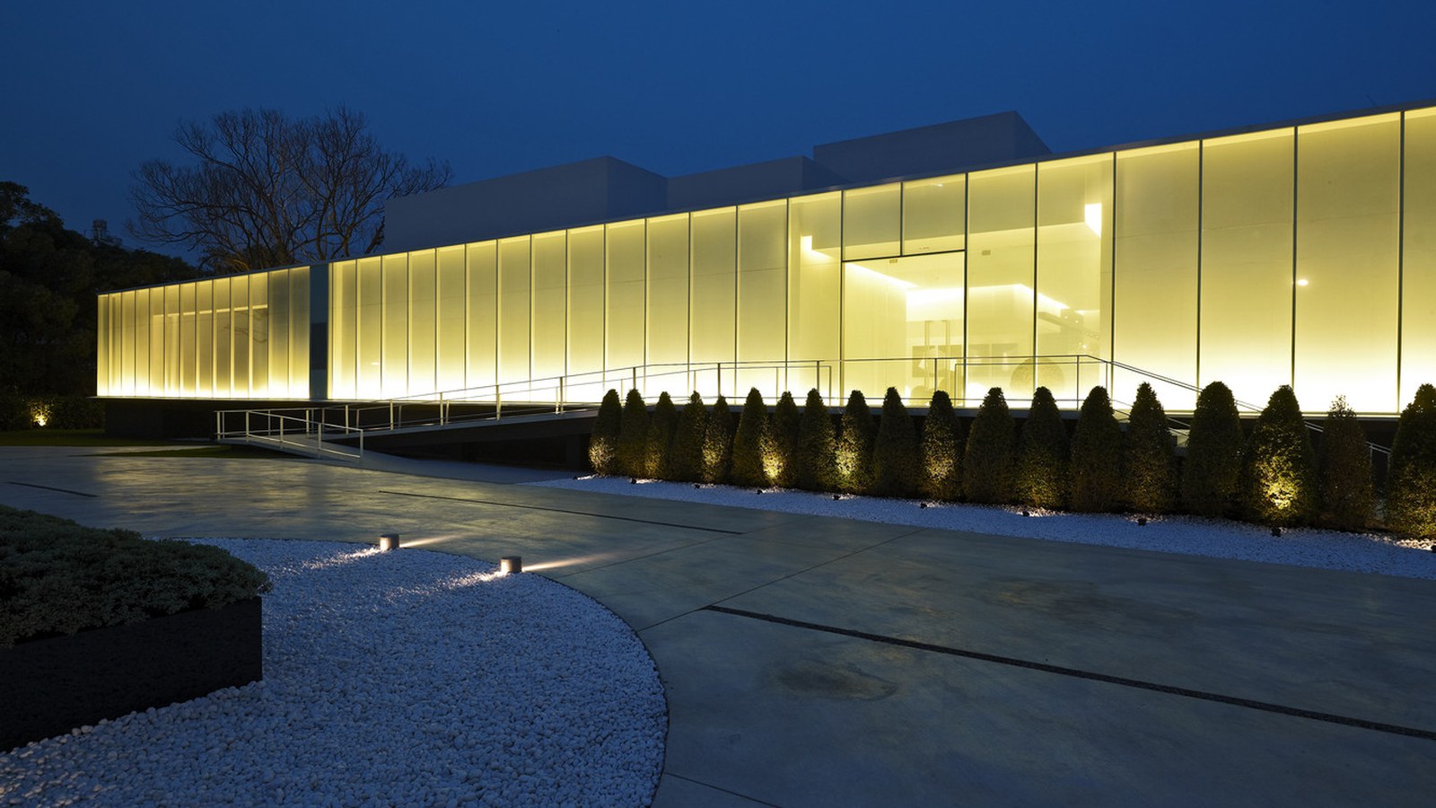 Curved building facade at dusk, lit by a continuous linear wall washer