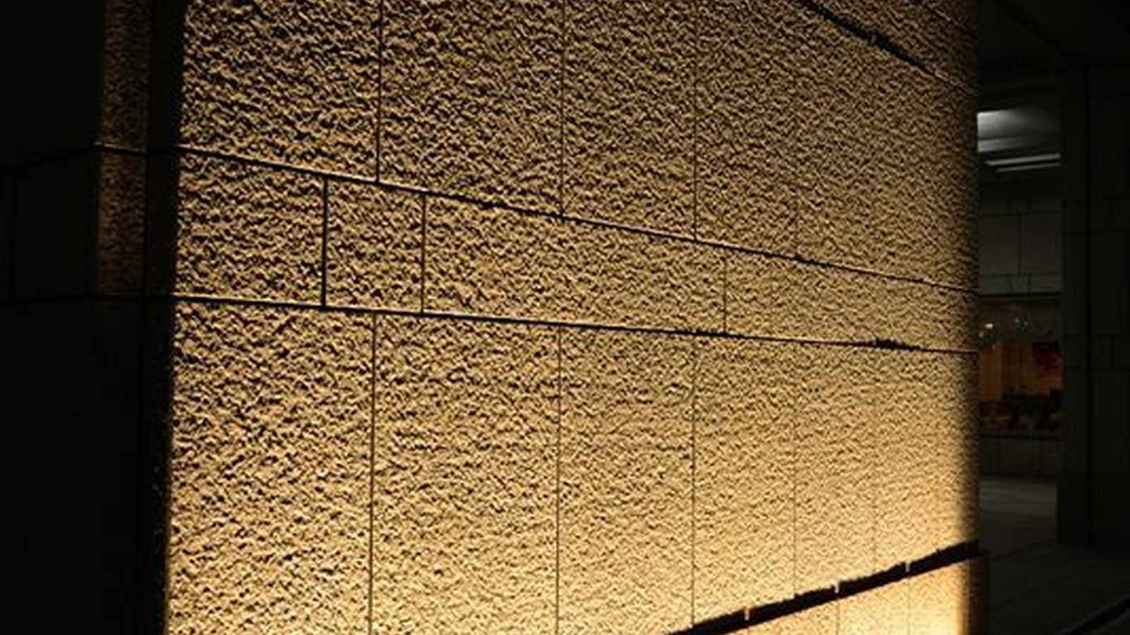 Textured stone feature wall lit evenly by a wall-washing light line